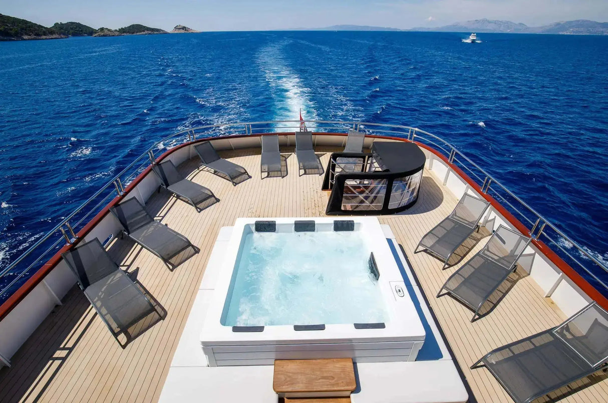 Witte moderne 6-persoons jacuzzi buiten op luxe jachtdek met zwemspa en ligstoelen.