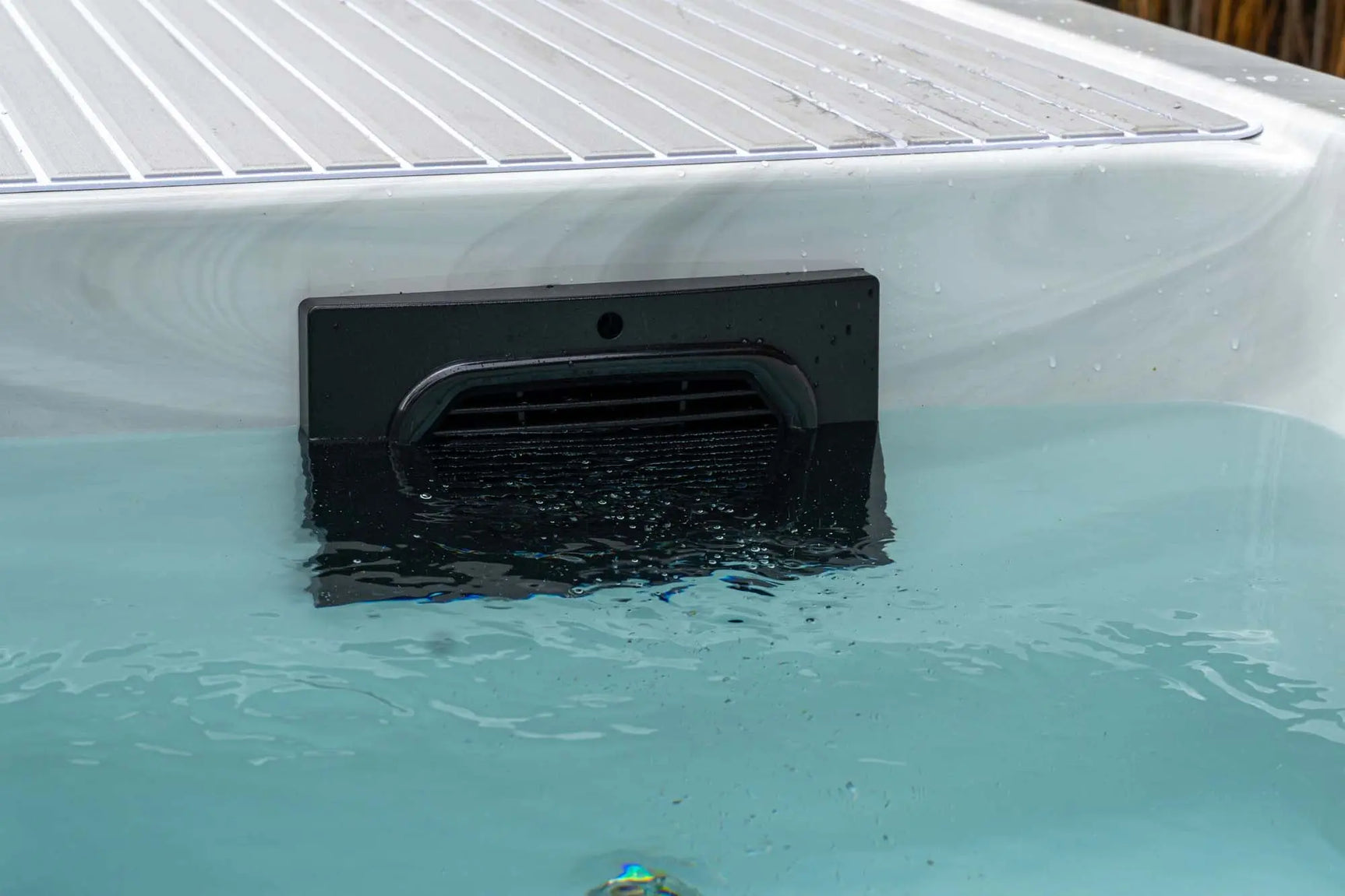 Witte jacuzzi buiten met helder blauw water en moderne waterinlaat voor swimspa of zwemspa.