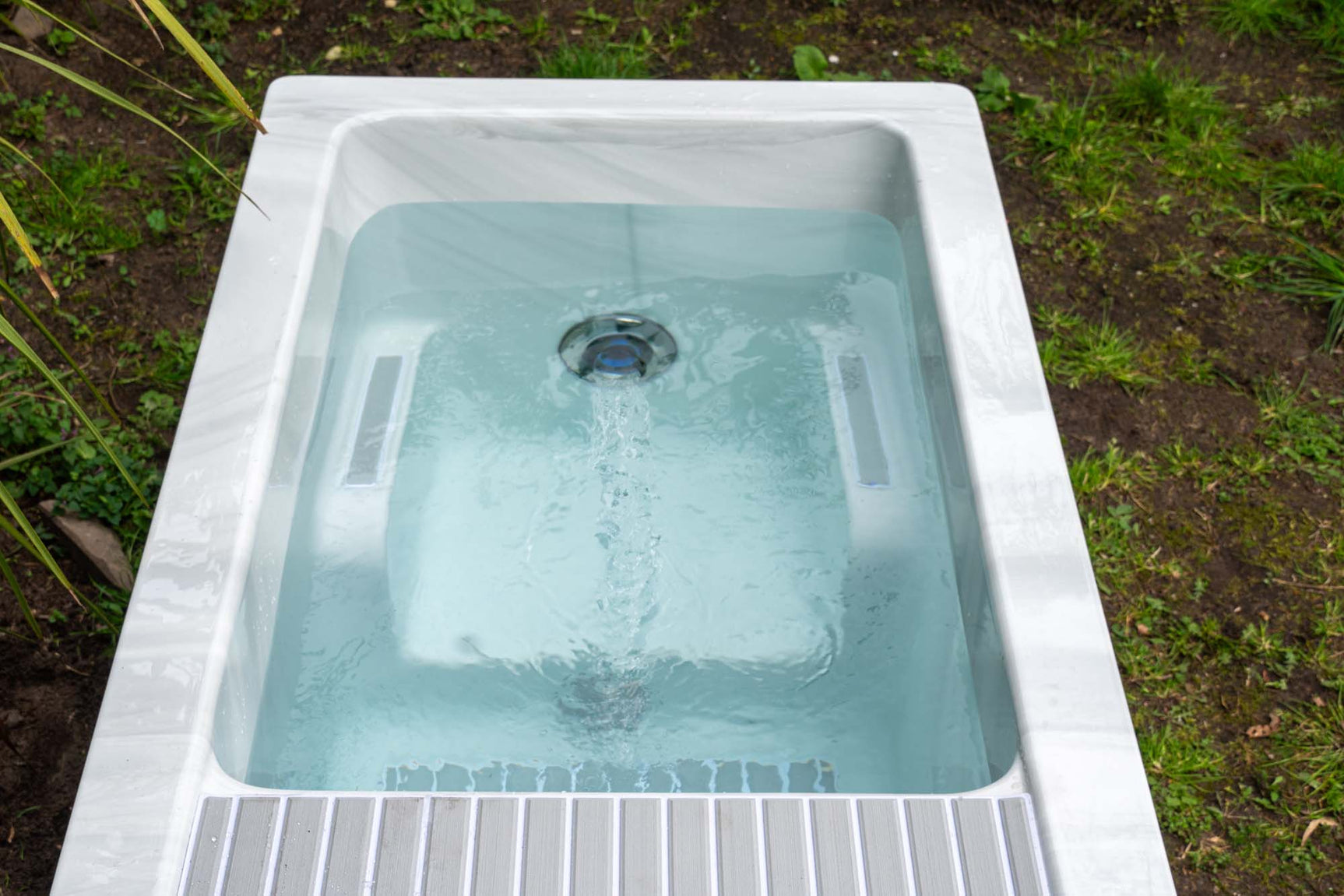 Witte jacuzzi buiten met helder water en geïntegreerde zitplaatsen, perfect voor zwemspa of swimspa.