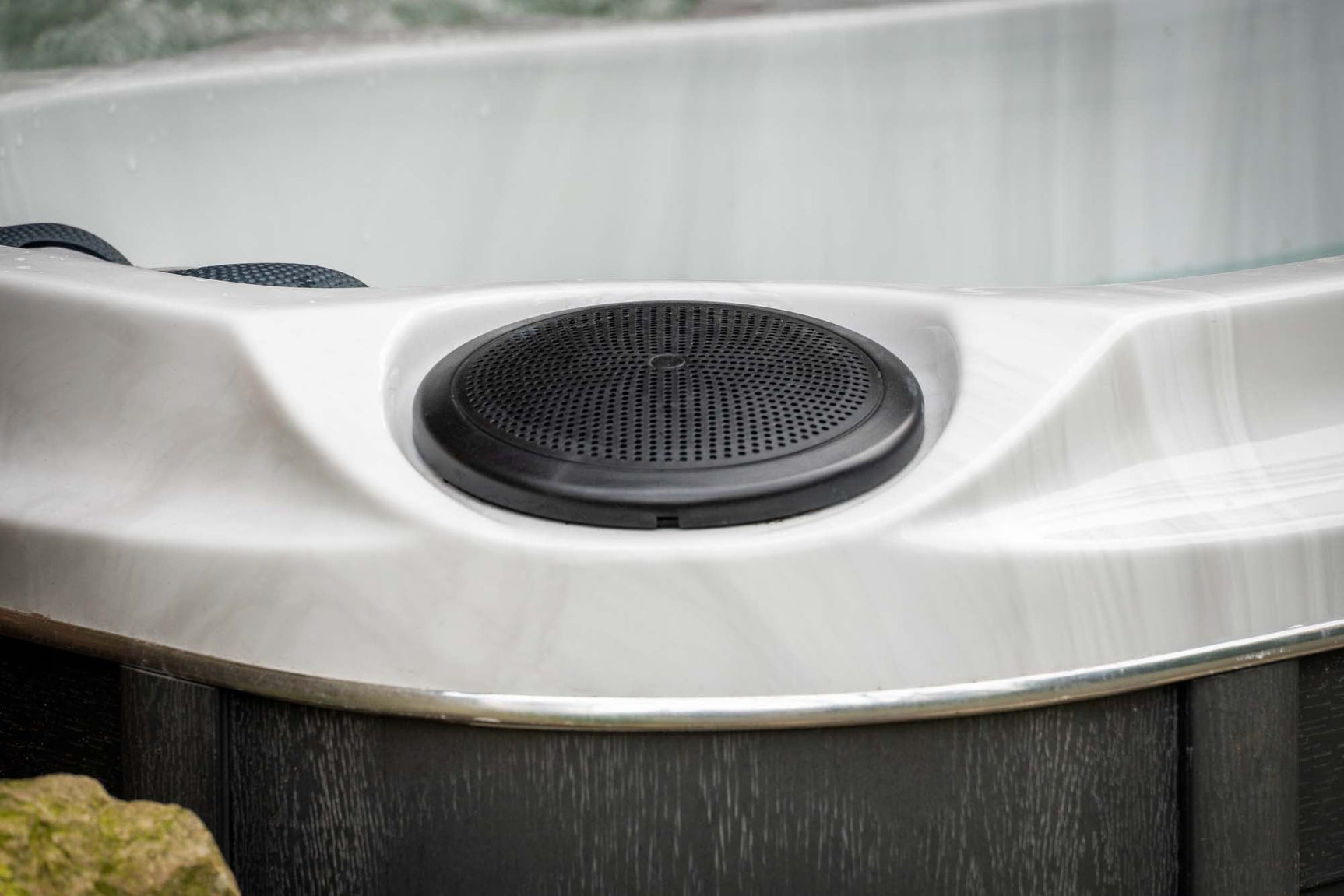 Close-up van zwart speakerrooster op witte rand van jacuzzi buiten, ideaal voor swimspa of zwemspa bij jacuzzi kopen.