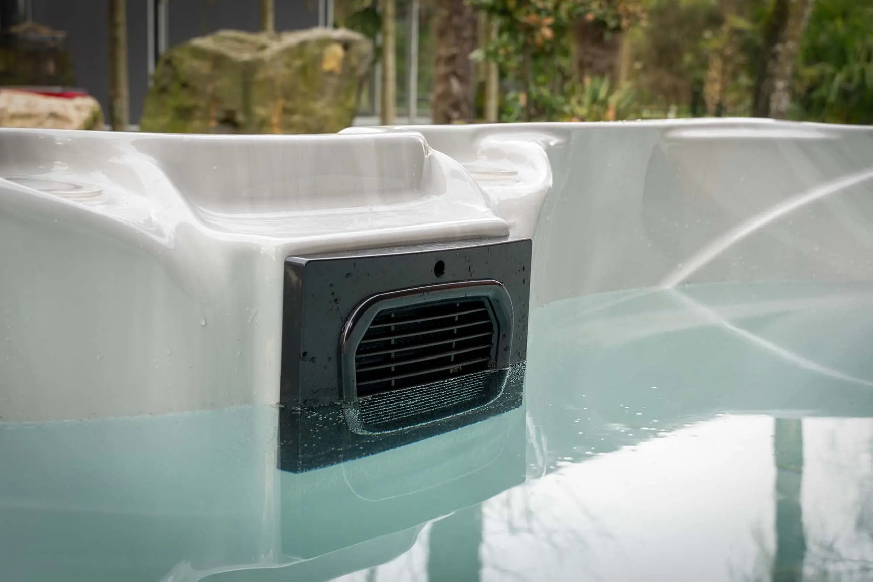 Grijze jacuzzi met water en ingebouwde luchtinlaat, perfect als zwemspa of jacuzzi buiten.