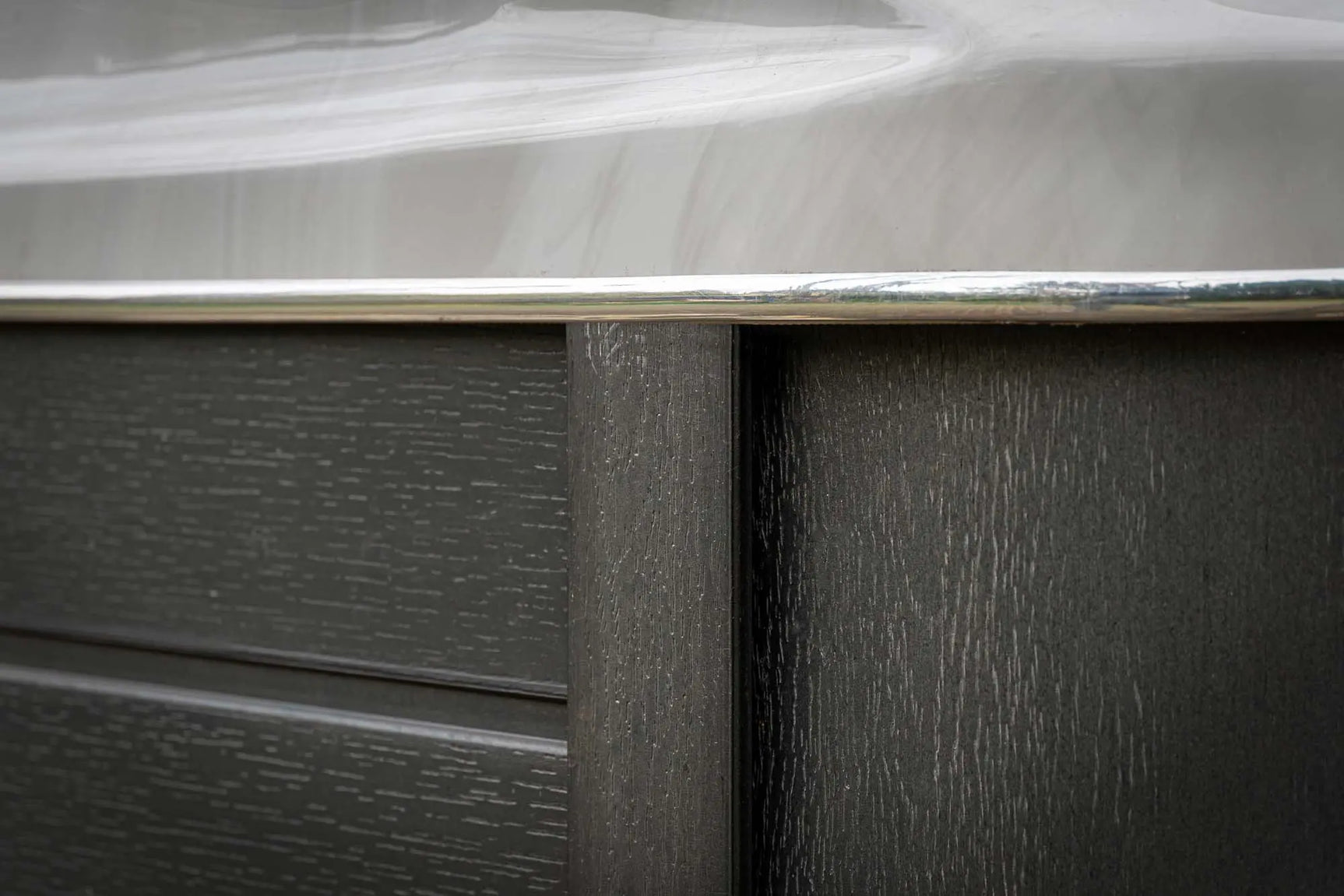 Close-up van hoek met houtstructuur en witte rand van jacuzzi zwemspa voor buitengebruik.