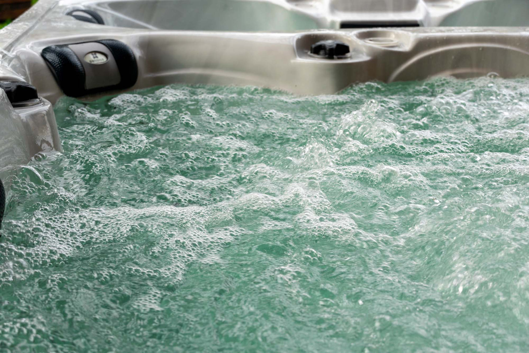 Witte jacuzzi buiten met bruisend water en comfortabele hoofdsteunen, ideaal als swimspa of zwemspa.