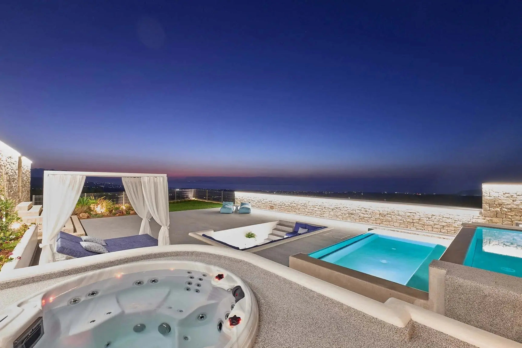 Luxe 7-persoons jacuzzi buiten met ingebouwde jets naast moderne zwemspa en swimspa bij zonsondergang.
