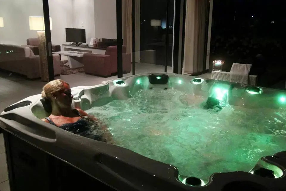 Zes persoons jacuzzi buiten met groene LED-verlichting en bubbeljets in moderne zwemspa.