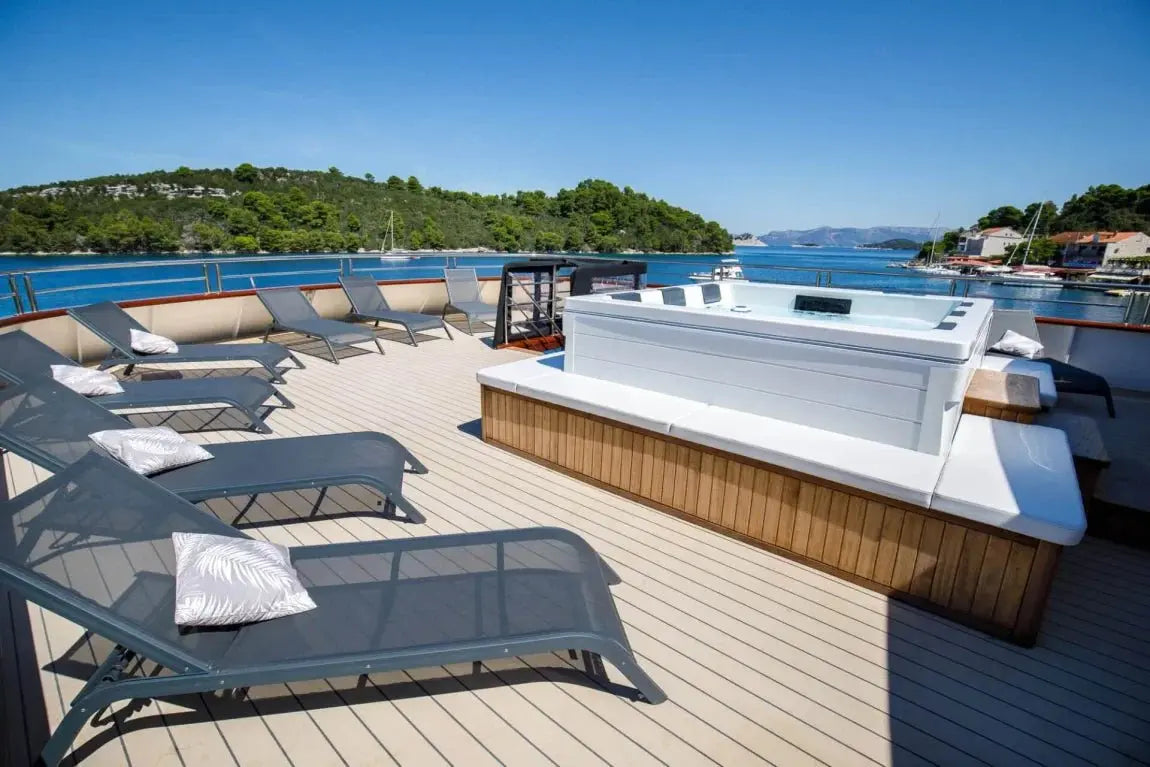 Moderne 6-persoons jacuzzi buiten met houten omlijsting, ligstoelen en uitzicht op zwemspa water.