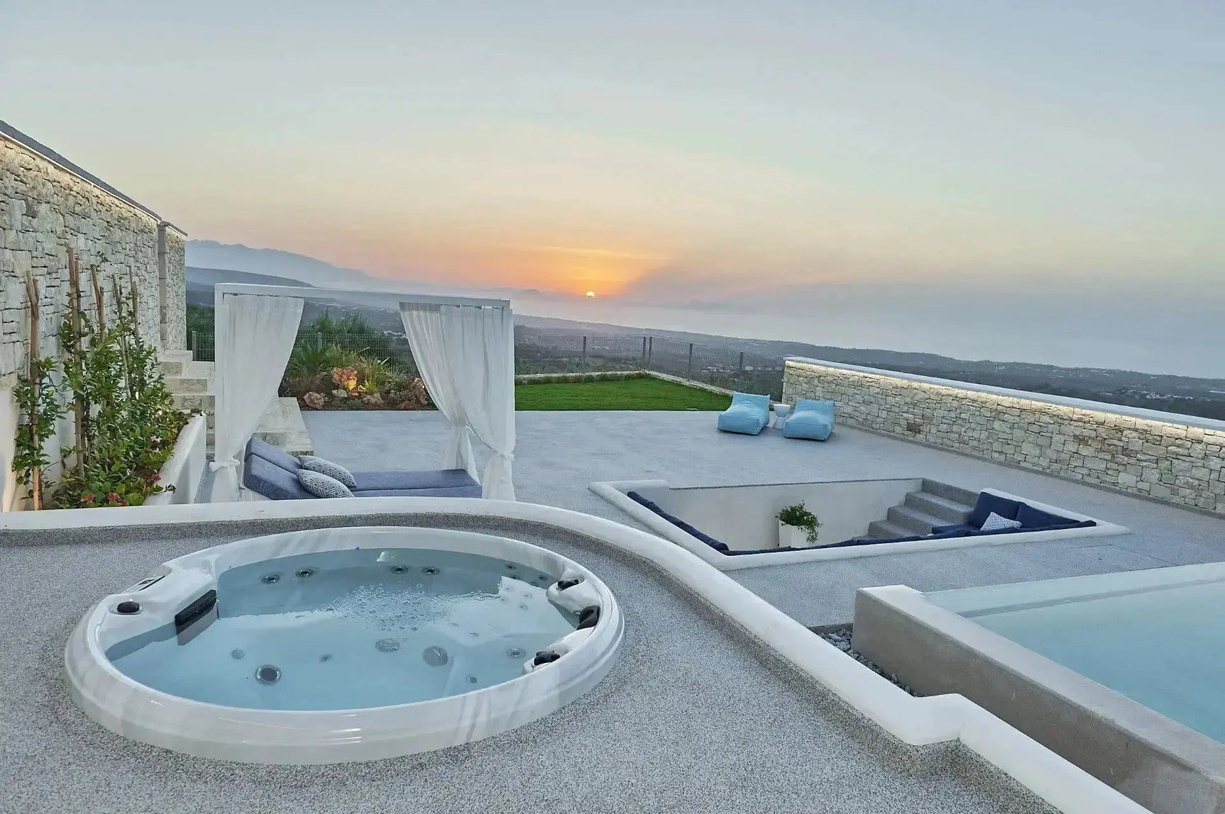 Ronde witte jacuzzi buiten met zitplaatsen en bubbeljets, luxe swimspa en loungestoelen in moderne tuin.