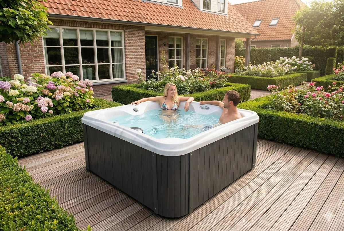 Twee personen in een vierkante spa op een vlonder bij een woning en bloeiende borders.