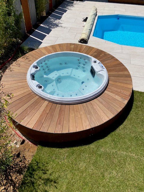 Recharge round hot tub with wooden deck surround in backyard setting near pool, by Passion Spas Pure Collection Hot Tubs