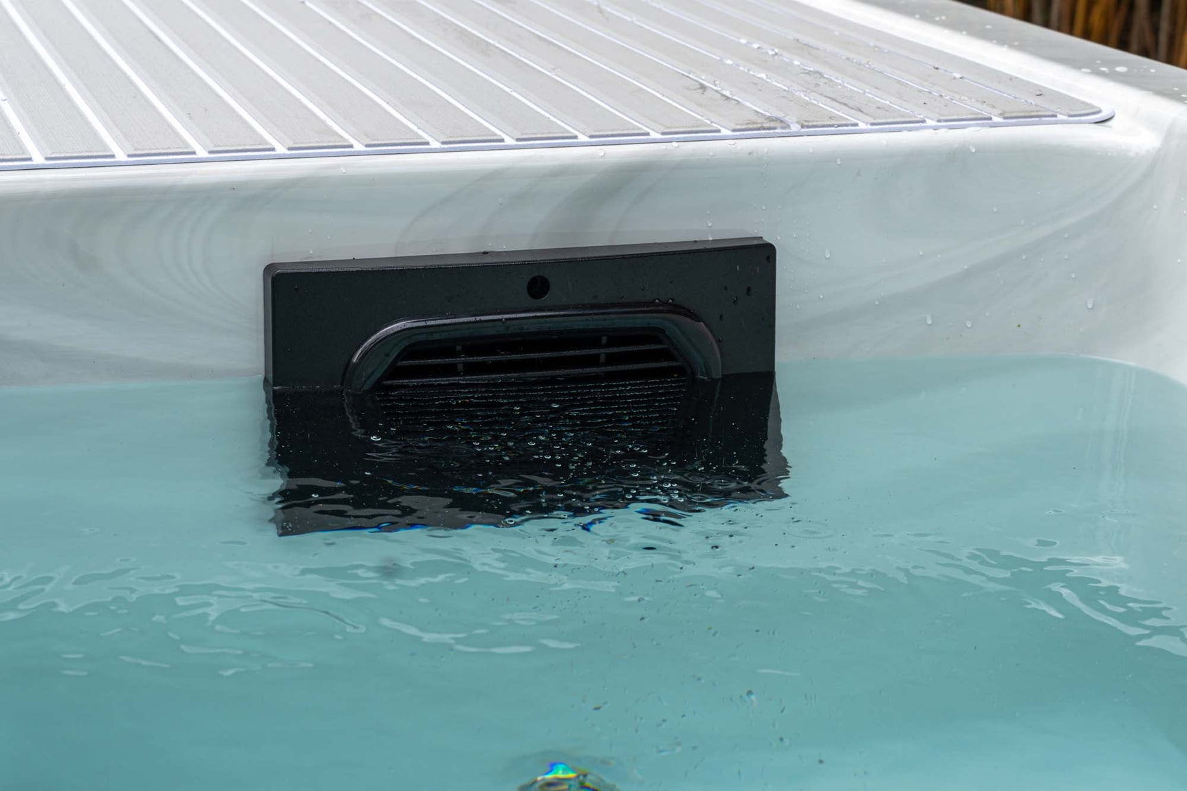 Witte jacuzzi buiten met helder blauw water en moderne waterinlaat voor swimspa of zwemspa.