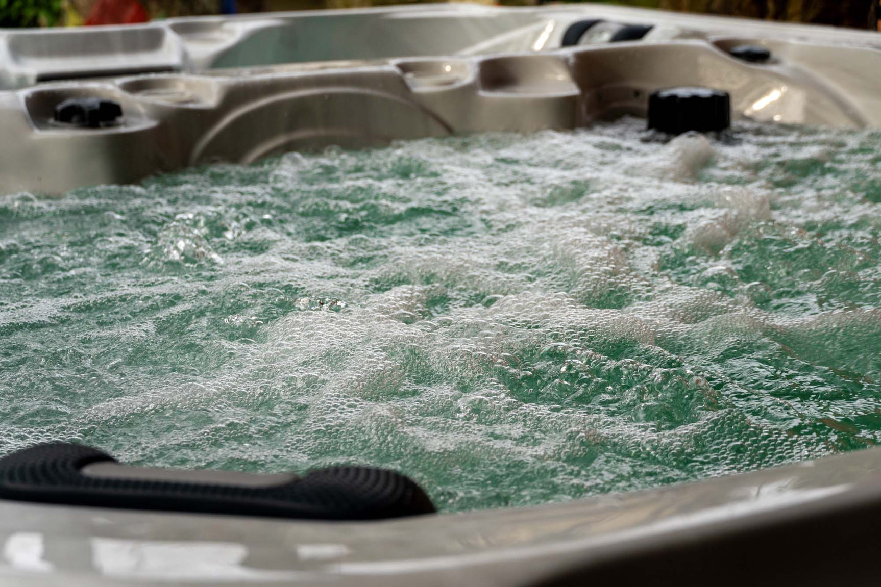 Bubbelend wit jacuzzi buiten met handgreep en watermassage, ideale zwemspa voor ontspanning.