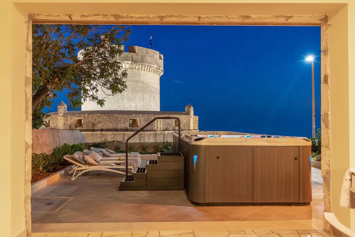 Moderne zwemspa Dynamic Deep als jacuzzi buiten met houten omkasting en trap, sfeervol verlicht bij nacht.