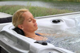 Person relaxing in Delight spa with therapeutic jets, showcasing luxurious lounger in outdoor setting - Passion Spas Signature Collection