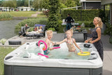 People enjoying the Desire hot tub from Signature Collection in a scenic backyard setting with water view - Passion Spas 6+ Person Hot Tub