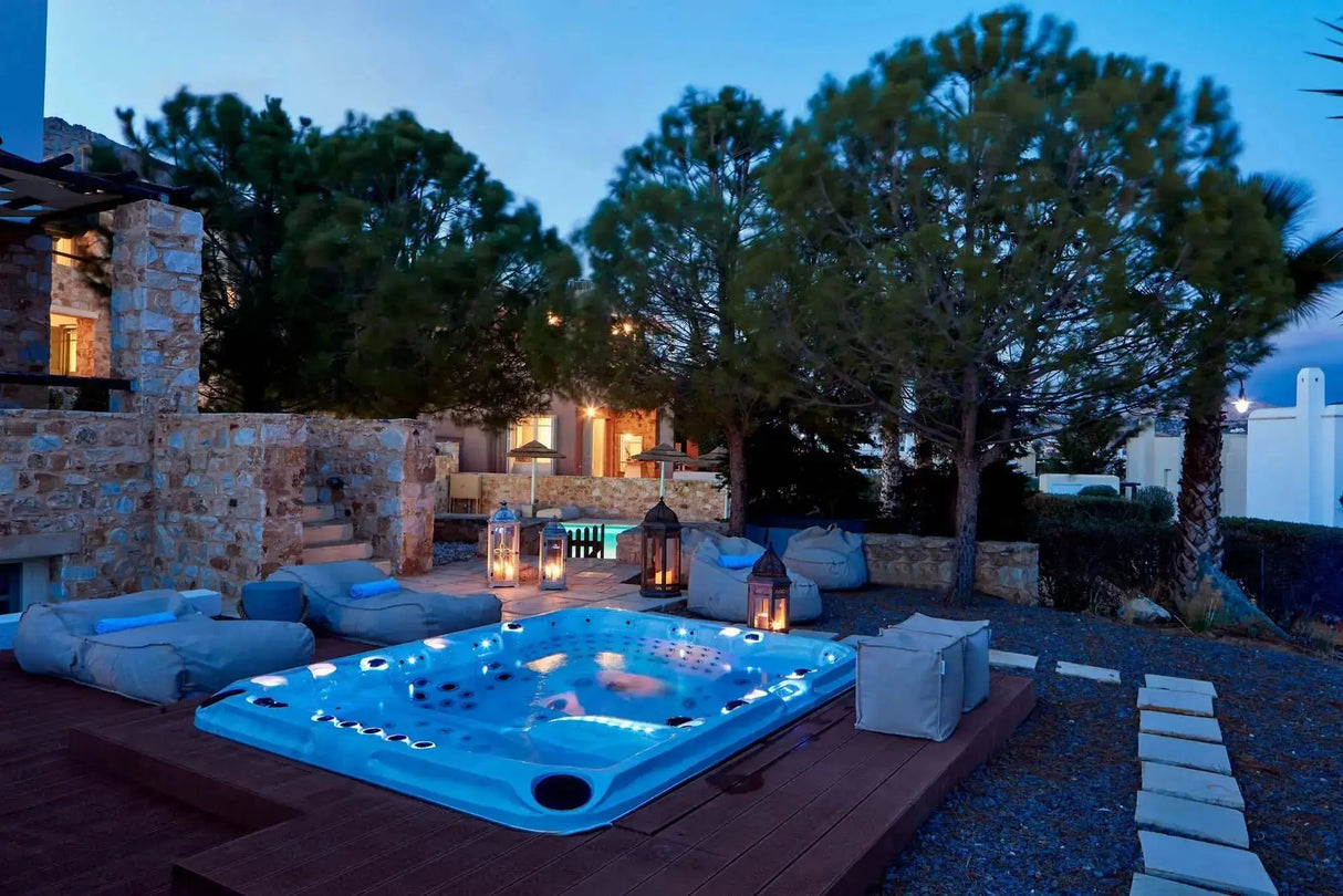 Luxe blauwe jacuzzi buiten met waterjets verlicht, onderdeel van exclusieve 7 persoons swimspa op houten terras.