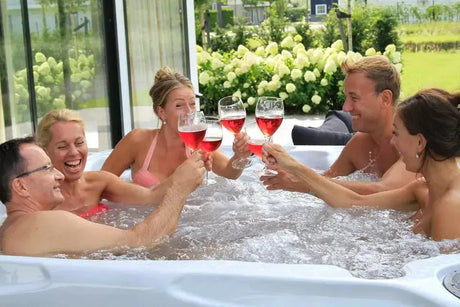 Vijfpersoons witte jacuzzi buiten met whirlpool jets en ontspannen mensen die toosten in swimspa.