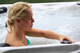 Person relaxing in Refresh spa with therapeutic jets, showing comfortable lounge seating - Passion Spas Pure Collection Hot Tub