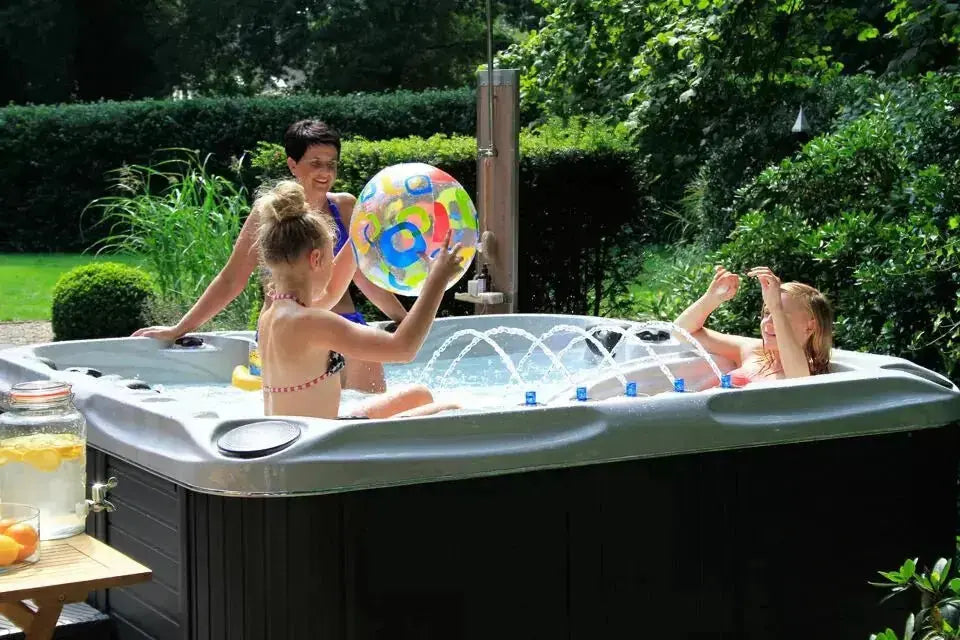 Zwarte 5-persoons jacuzzi buiten met waterjets en kinderen spelend in zwemspa.