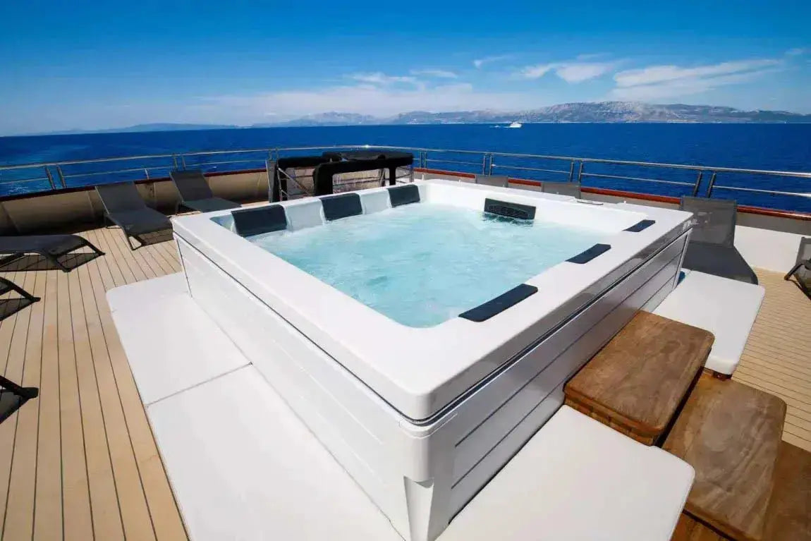 Moderne witte 6-persoons jacuzzi buiten op terras met uitzicht op zee, ideaal als zwemspa of swimspa.