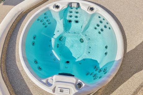 Ronde witte 7-persoons jacuzzi buiten met blauwe waterkleur en geïntegreerde zitplaatsen, ideaal als zwemspa of swimspa voor .